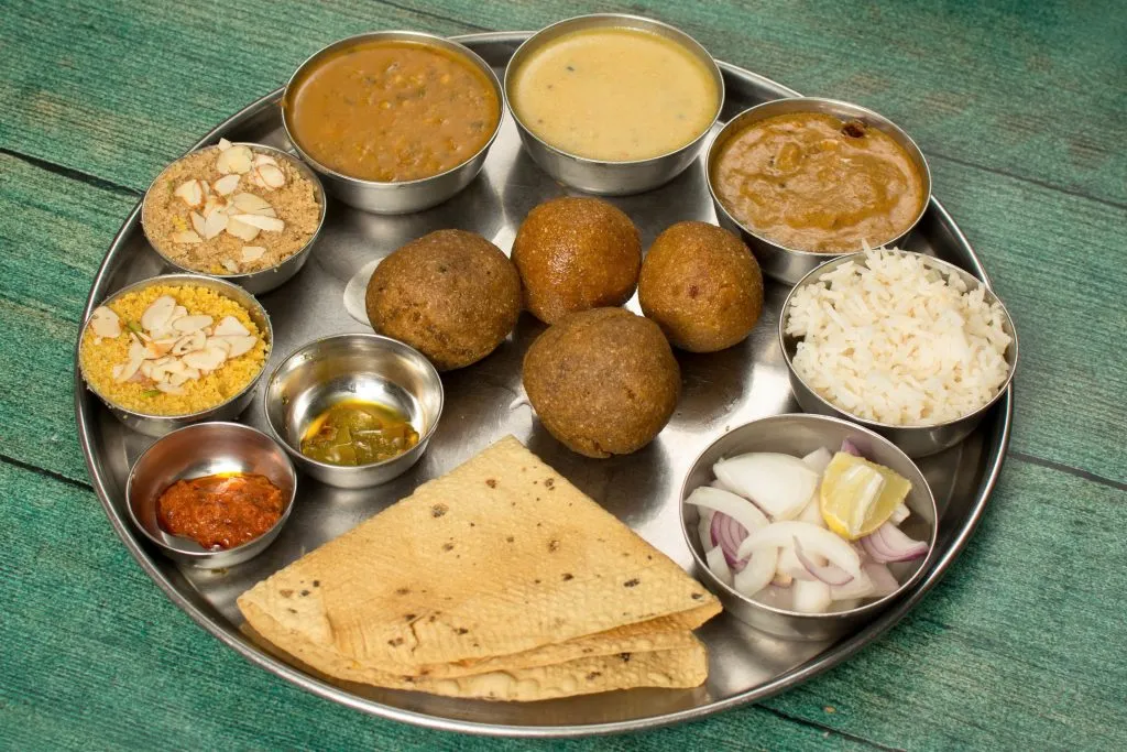 Dal baati churma thali with several bowls and wheat baatis